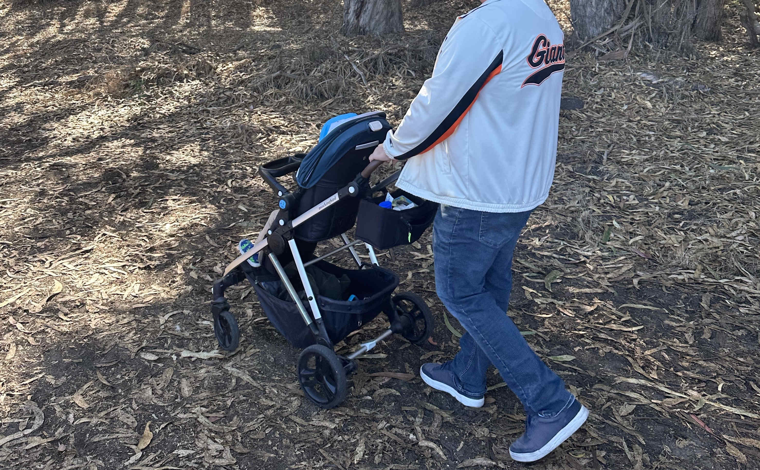 The mockingbird stroller being pushed through dirt and leaves.