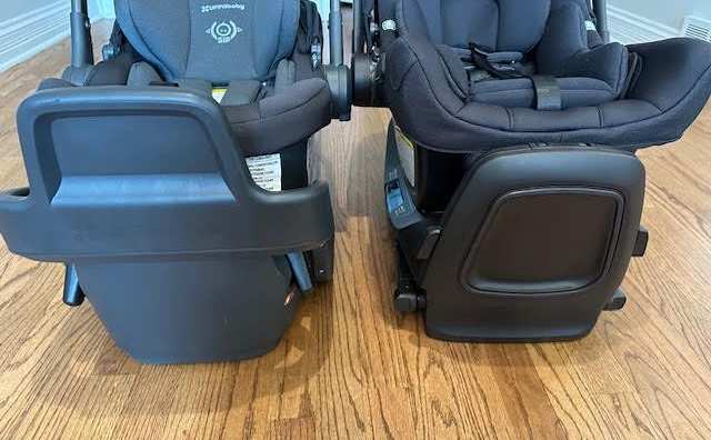 A side-by-side shot of two all black infant car seats: the UPPAbaby Aria and the Nuna Pipa Rx. The shot focuses on the seats' integrated anti-rebound panels.