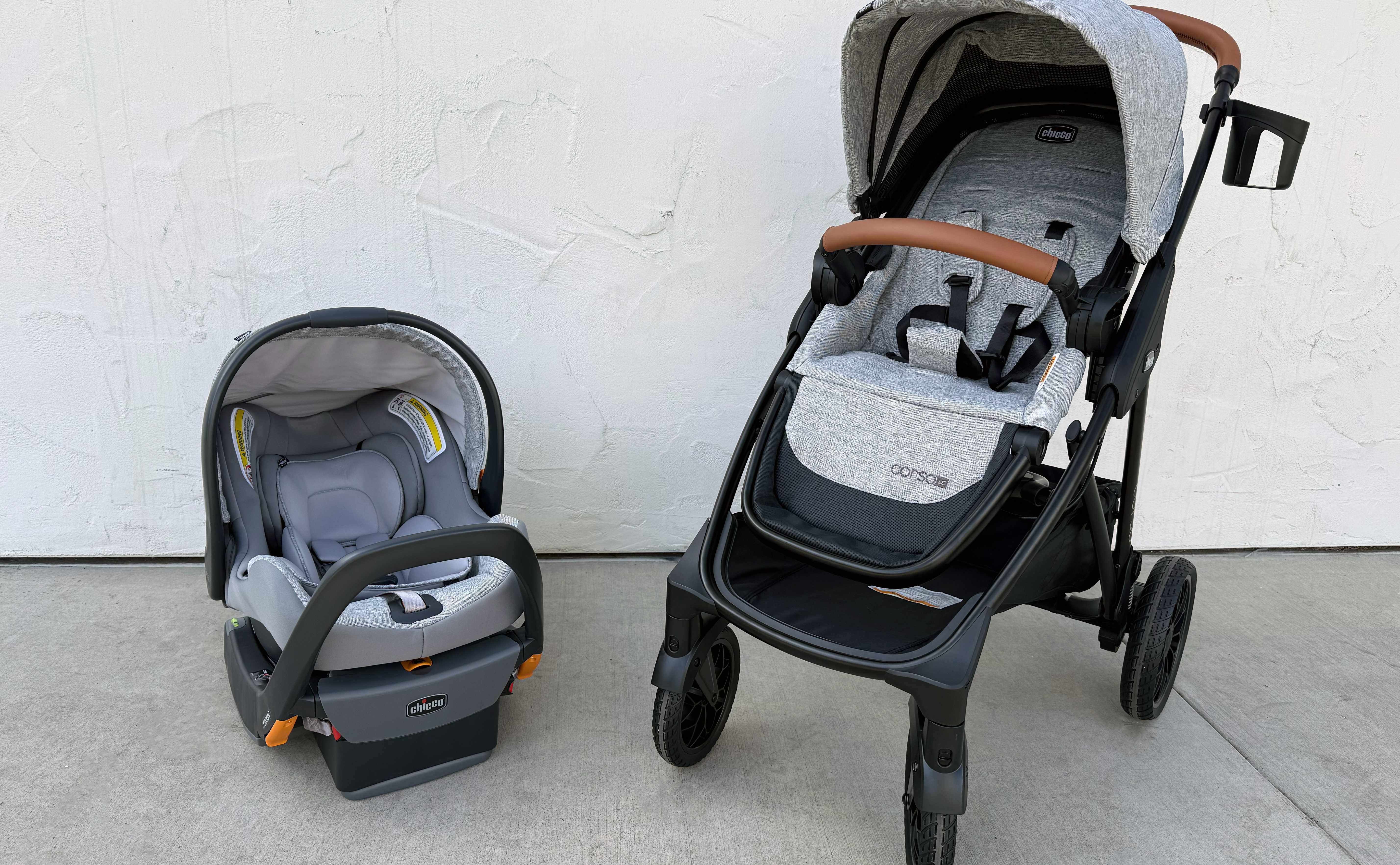 A head-on shot of the two components of the Chicco Corso LE Travel System: an infant car seat with a gray canopy and a stroller with a gray canopy.