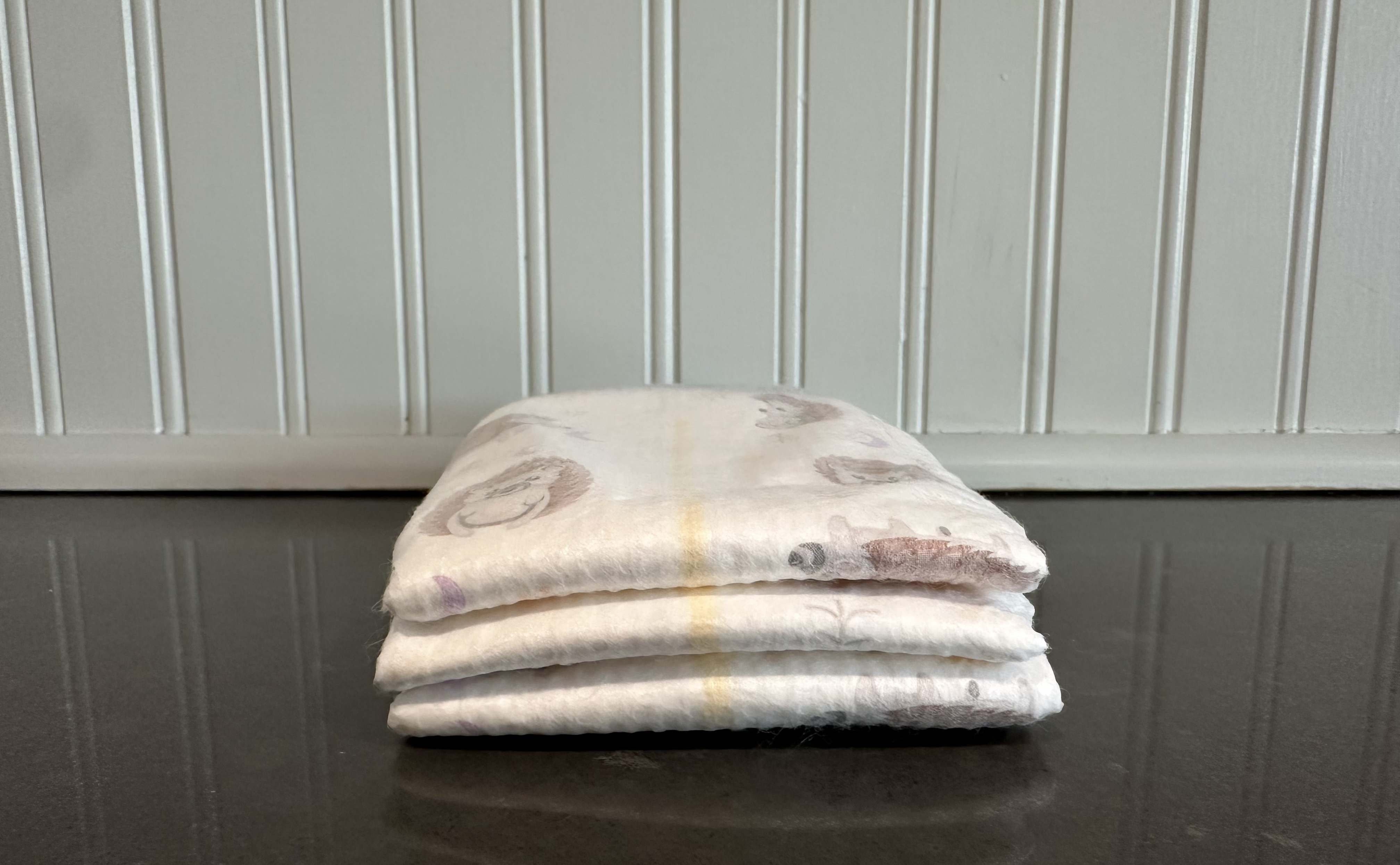Stack of 3 Kirkland diapers on a black counter.