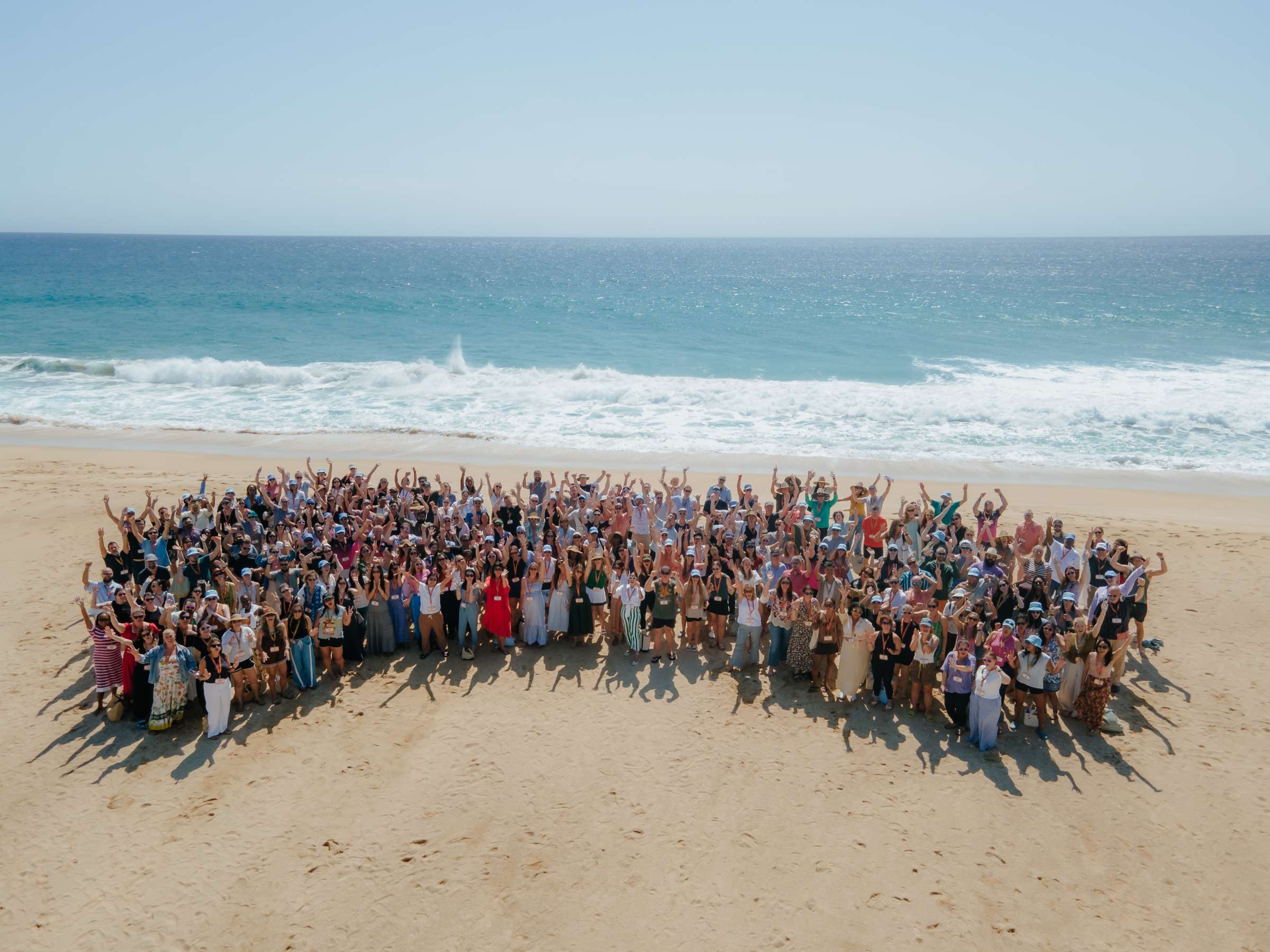 Babylist team gathered on a sunny beach, waving at the camera