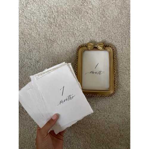 Newborn Baby Milestone Cards on textured paper with vintage frame