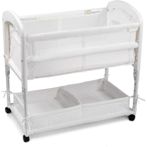 Arm’s Reach Cambria Co-Sleeper Bedside Bassinet Featuring Height-Adjustable Legs, Curved Wooden Ends, Breathable Mesh Sides with Pockets, and Large Lower Storage Basket, White