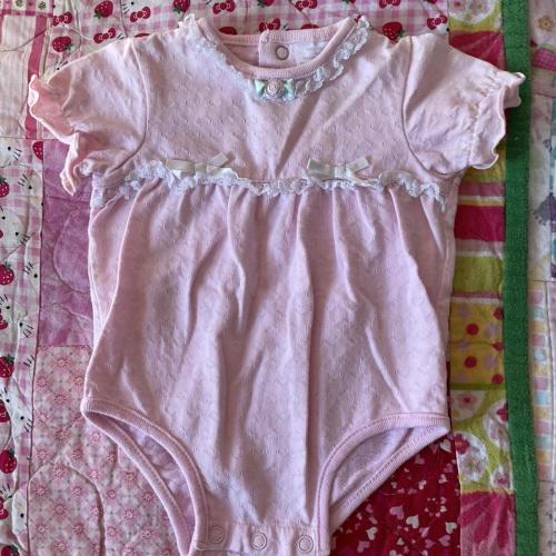Pink baby onesie with lace and bow details. Size:...