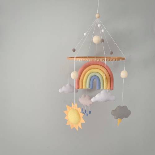 Rainbow nursery decor with sun, cloud with raindrops, cloud with lightning in pastel color palette. Weather baby mobile with felt balls