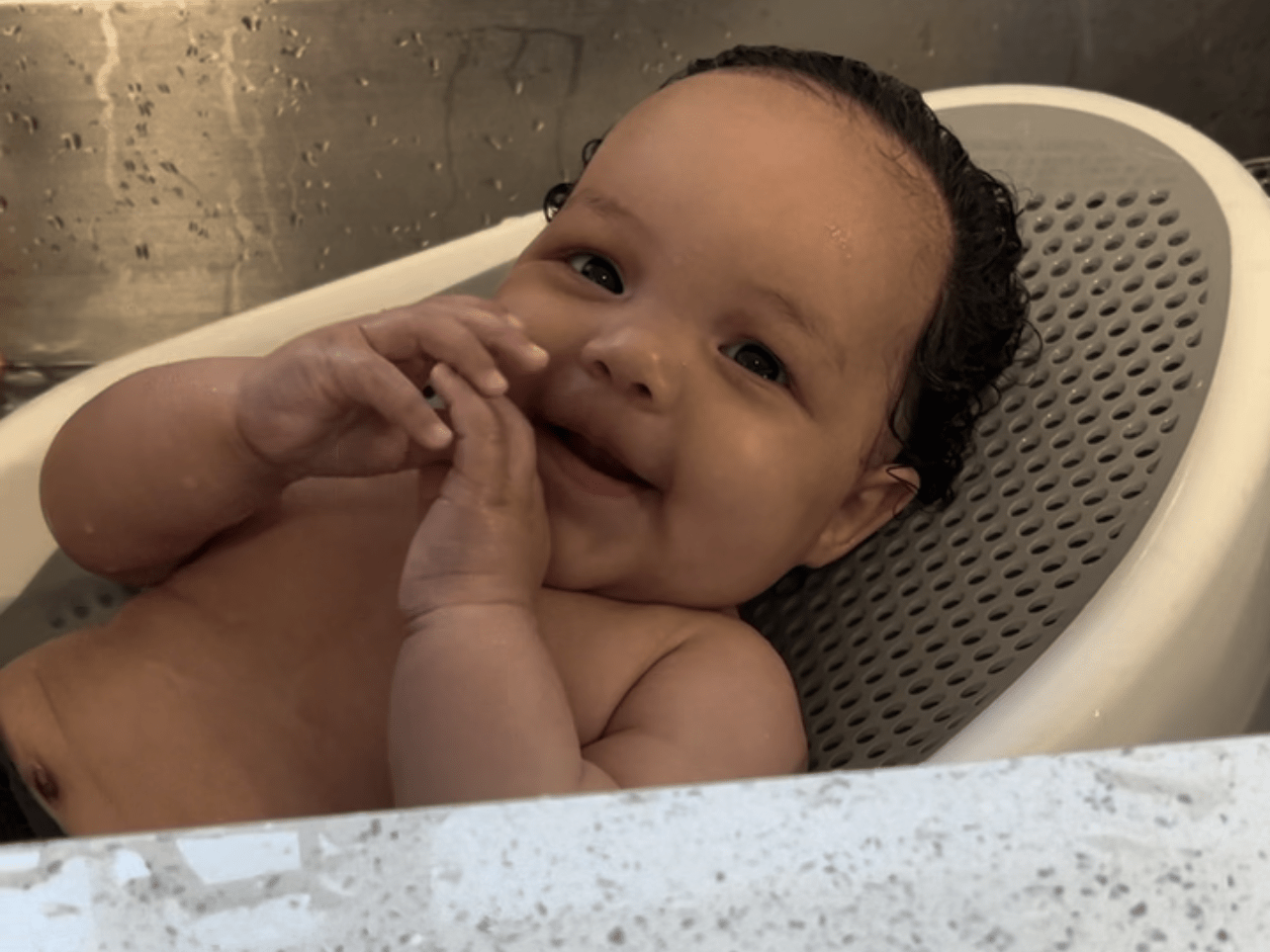 Baby in Angelcare bath support in kitchen sink.