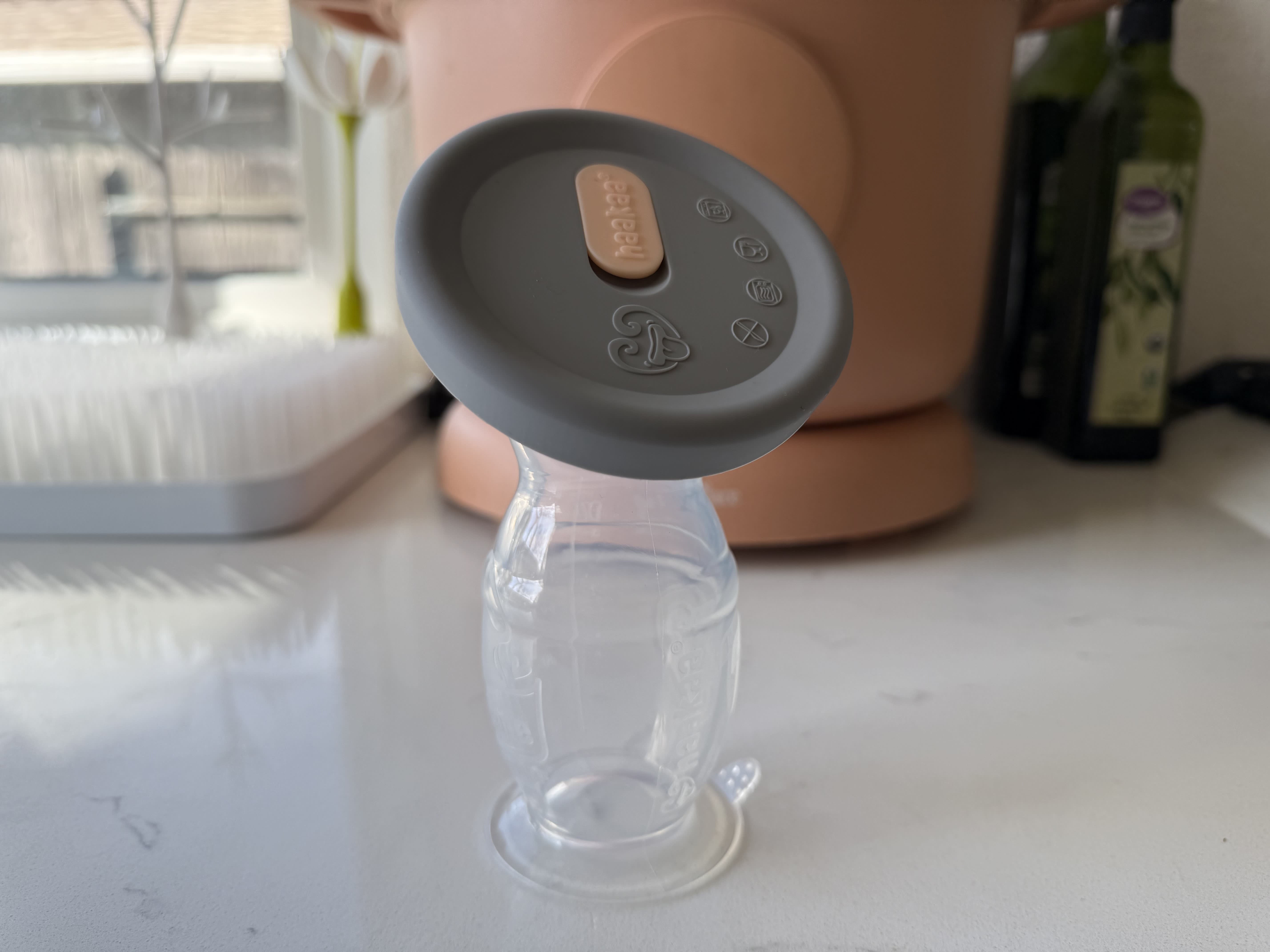 Haakaa silicone pump with a lid suctioned on a kitchen counter.