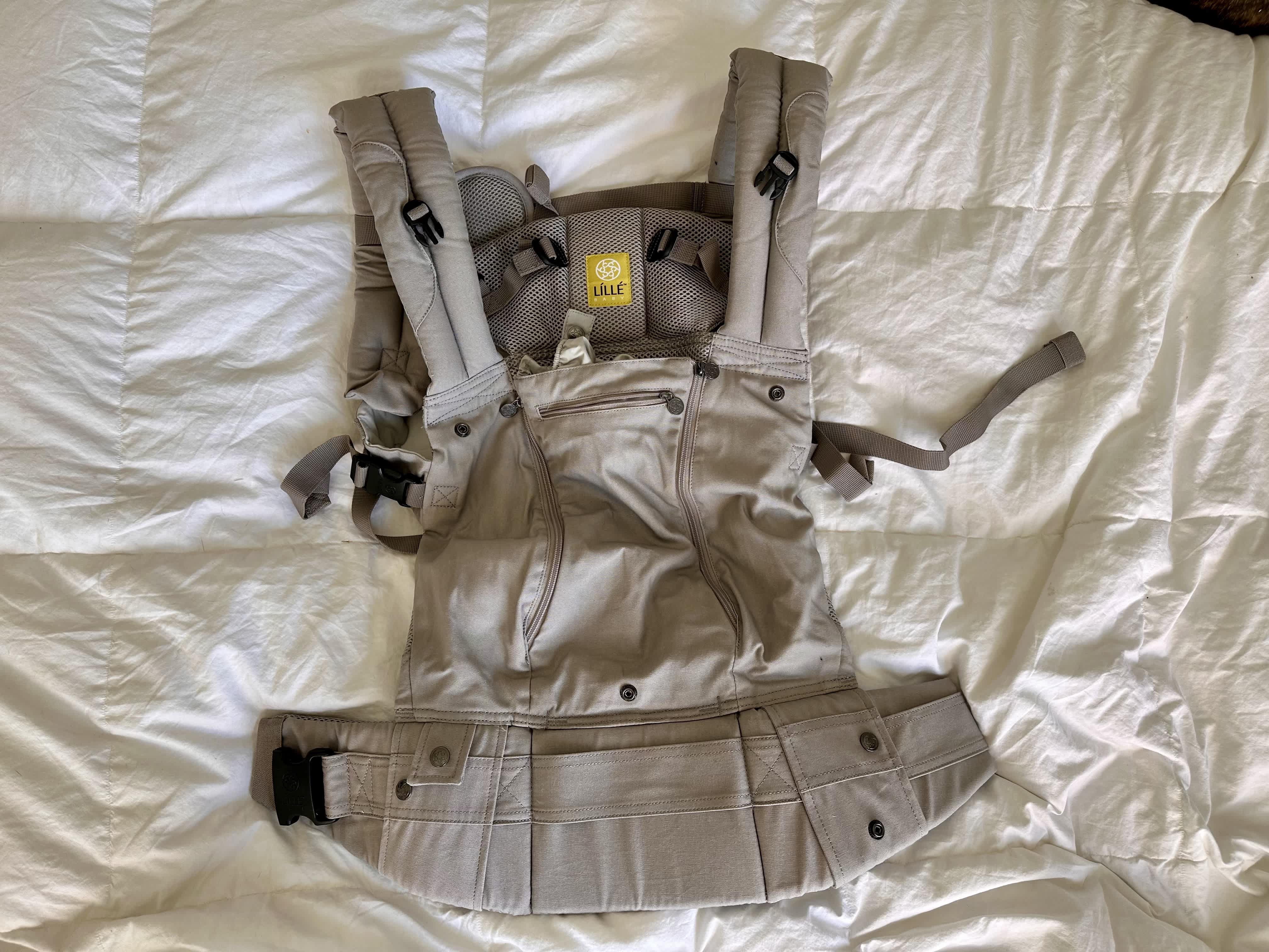 The Lillebaby Complete All Seasons 6-1 Baby Carrier in Stone laying flat on a white comforter.