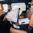 Nuna urbn infant car seat with light beige canopy and fabrics installed rear-facing in vehicle with tan interior thumbnail.