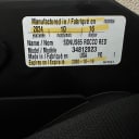 Close-up of a white date of manufacture label on a black car seat shell showing important safety details, including the date of manufacture, expiration date, model name, and number. thumbnail.