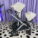 A side view of an UPPAbaby Vista V3 Stroller with beige canopies in double mode, with one toddler seat parent-facing and one toddler seat world-facing. thumbnail.