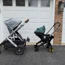 A side-by-side shot of an UPPAbaby Vista stroller with a gray canopy next to a Doona with a green canopy. thumbnail.