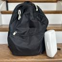 A black backpack-style diaper bag resting on a stair next to a white OXO Tot On-The-Go Drying Rack & Bottle Brush. thumbnail.