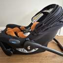 Side view of a small doll harnessed into a Joie Mint Latch Baseless Infant Car Seat in black. thumbnail.