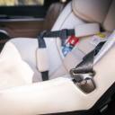 A close-up of the buckle holders on the side of a beige Nuna Rava Convertible Car Seat. thumbnail.