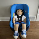 A head-on shot of a Cosco Kids Scenera Next Convertible Car Seat with blue fabric with a toddler-sized doll strapped in thumbnail.