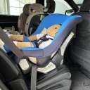 A Cosco Kids Scenera Next Convertible Car Seat with blue fabric installed rear-facing in a Jeep Grand Cherokee L with a toddler-sized doll strapped in thumbnail.