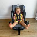 A toddler with light skin and blonde hair buckled into the Graco SlimFit3 LX 3-in-1 Convertible Car Seat. The car seat is not installed in a vehicle, it's resting on a light wooden floor. thumbnail.