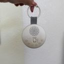 A hand holding the white Sprucely Travel Sound Machine by its detachable hook. thumbnail.