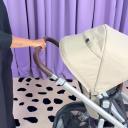 A woman wearing a black sweatshirt moves the telescoping handlebar up and down on the UPPAbaby Vista V3 Stroller. thumbnail.