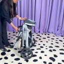 A woman in a black sweatshirt and blue hat folding the UPPAbaby Vista V3 stroller. thumbnail.