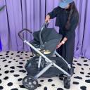 Woman in black sweatshirt and blue hat puts UPPAbaby Aria Infant Car Seat into UPPAbaby Vista V3 Stroller. thumbnail.