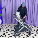 A woman in a black sweatshirt and blue hat changes the direction of the modular toddler seat on the UPPAbaby Vista V3 stroller. thumbnail.