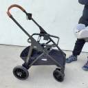 A man in a black sweatshirt and black pants take an infant car seat in and out of the Chicco Corso LE Modular Travel System stroller frame. thumbnail.