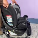 A person wearing brown pants rotates the Evenflo Revolve360 Extend car seat while it's placed on the floor. thumbnail.