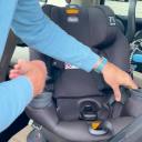 A man with white skin and a blue shirt rotates the Chicco Fit360 car seat in a vehicle. thumbnail.